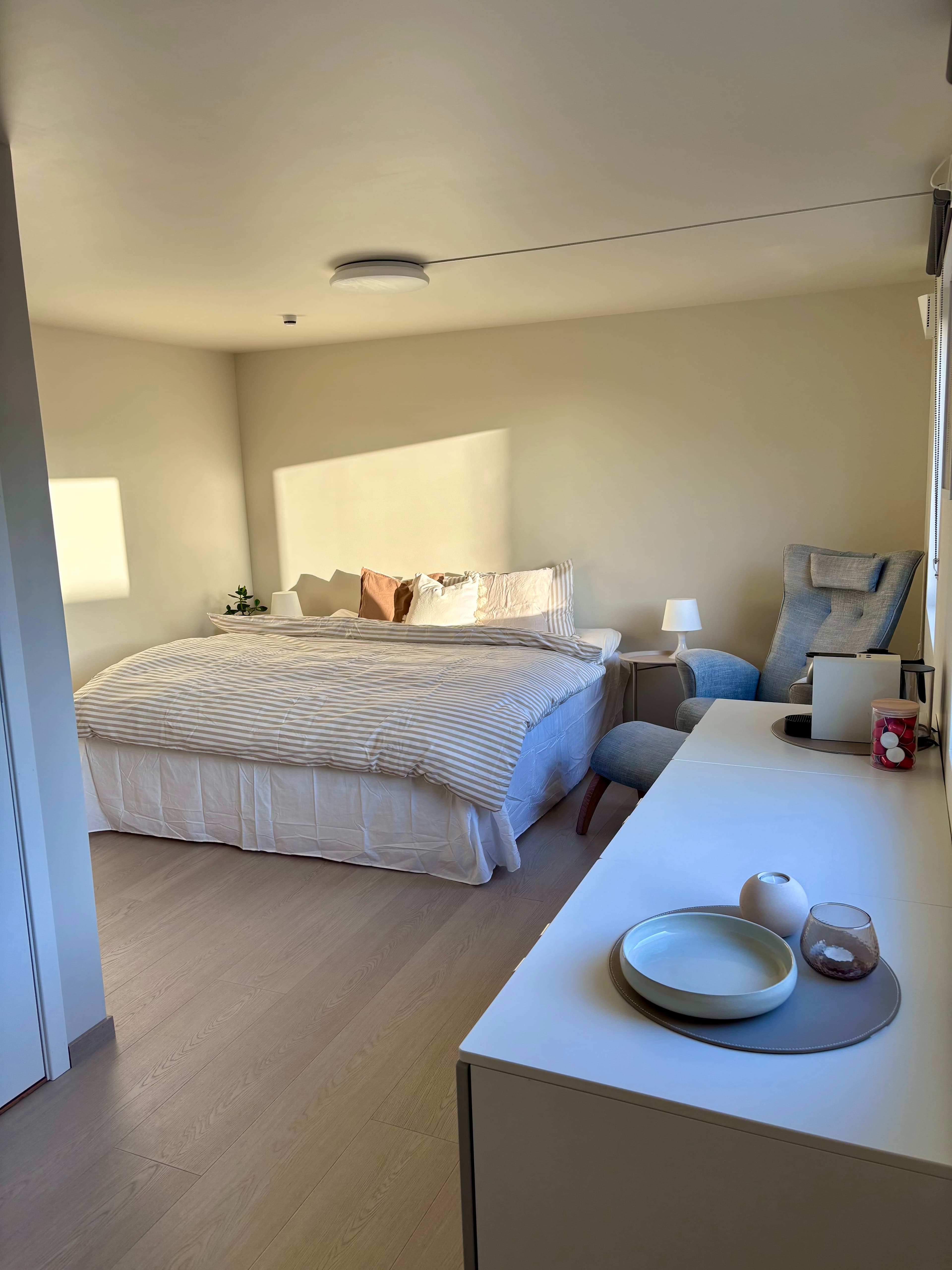 Rommet på Forus Hotell – seng, lenestol og sidebord i varmt morgenlys